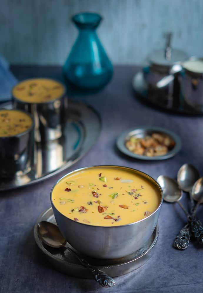 carrot payasam displayed on a stainless steel bowl with lots of nuts garnished. 